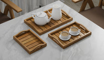 A Set of 3 Teak Trays with Arched Handle serving tea.