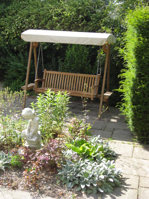 Teak Swing Seat with Ecru Canopy in the garden