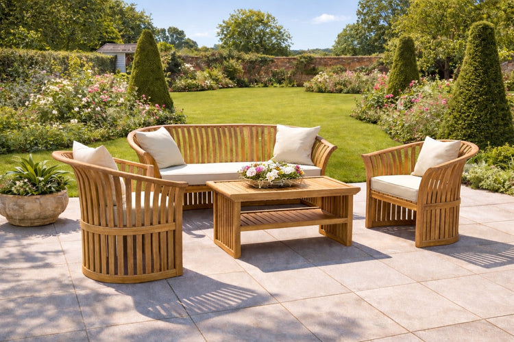 Teak curved outdoor lounge set with a 2 seater sofa, 2 lounge armchairs and a coffee table set on a patio with a beautiful garden behind